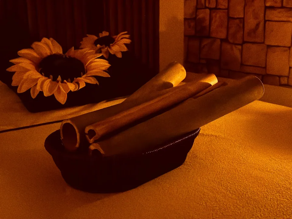 Cañas de bambú preparadas para una sesión de masaje, junto a flores en el spa.